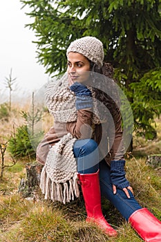 Posing autumn woman sitting in pinewood forest photo