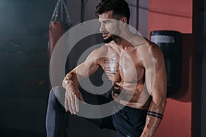 Posing bodybuilding man shows his muscle in a black studio in front of the camera wearing professional sportswear