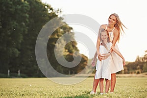 Posing for a camera. Mother and daughter enjoying weekend together by walking outdoors in the field. Beautiful nature