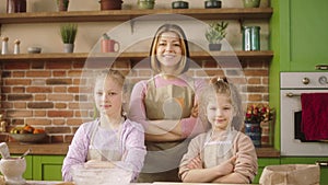 Posing in front of the camera amazing looking woman and her two kids girls at the kitchen island they crossing hands and