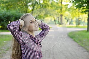 A posing girl 11 years old on a road in a park. Against a background of trees and grass.