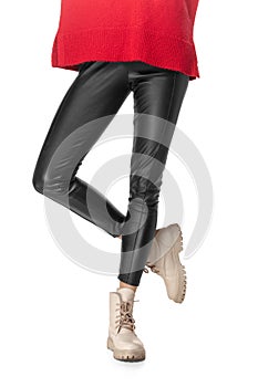 Slim legs of young girl in black leggings and boots isolated on white background