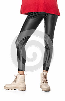 Slim legs of young girl in black leggings and boots isolated on white background