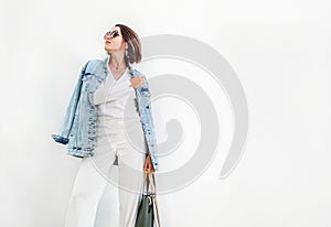 Posing woman in elegant white color outfit with oversize denim j