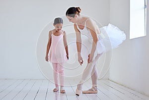 Position your feet like this. Shot of a little girl practicing ballet with her teacher in a dance studio.
