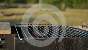 Positioned on the barbecue, the grill grate sits as the fire rages within, casting a warm glow