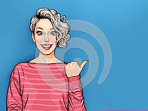 Positiv beautiful smiling woman with curly hair   point at something with thumb, has good mood, isolated on blue background.