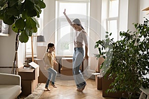 Positive active mom and kid dancing at new home