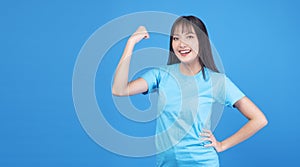 Positive active strong Asian woman proud on blue background. Confident slim body young girl wears casual showing fist have good