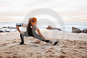 Positive adult european woman in sportswear doing stretching for legs, warming up, enjoy workout