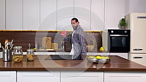 Positive adult man with beard doing household chores domestic kitchen