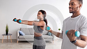 Positive African American couple exercising with dumbbells at home during covid-19 lockdown, panorama
