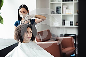 Positive african american girl enjoying hairstyling at reopened beauty salon