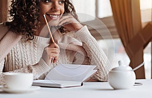 Positive African American woman making notes in the cafe