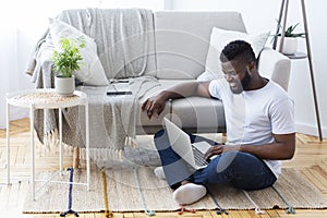 Positive african man surfing internet on laptop