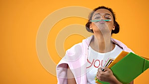 Positive african teenager holding pencil between nose and lips, mustache joke