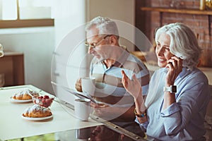 Positive aged couple having breakfast in the kitchen
