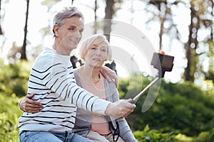 Positive aged couple taking selfie outdoors