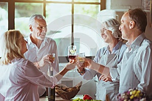 Positive aged couples celebrating in the kitchen