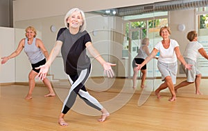 Positive aged woman practicing vigorous dance movements photo