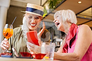 Positive aged woman showing her smartphone to a friend