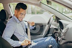 Positive arab guy fastening seatbelt, safety driving concept