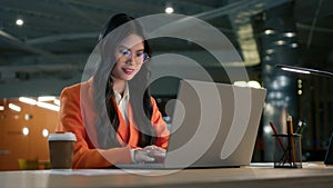 Positive Asian American female executive manager businesswoman sitting at desk