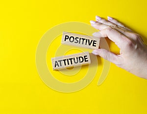 Positive attitude symbol. Concept words Positive attitude on wooden blocks. Beautiful yellow background. Businessman hand.