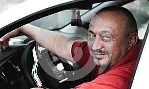 Positive attractive man sitting behind the wheel of a car