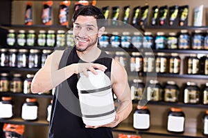 Positive attractive sportman demostration sport nutrition in shop photo