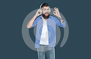 positive bearded man listen to music in headphones. ok