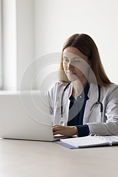 Positive beautiful practitioner woman using laptop computer at work table