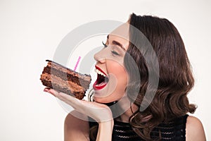 Positive beautiful woman biting piece of chocolate birthday cake