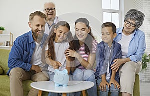 Positive big family throws coins into piggy bank collecting money for car, travel and education.
