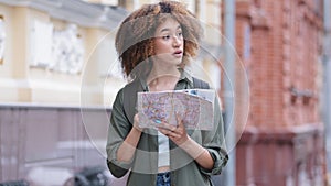 Positive biracial young african american woman hiker with backpack holding travel map. Traveling curly-haired black