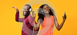 Positive black couple with wireless headsets having fun on yellow