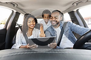 Positive black family have car ride, using digital tablet