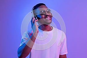 Positive Black Guy Wearing Wireless Headphones And Sunglasses Listening Music