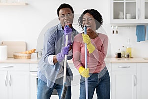 Positive black man and woman cleaning house and having fun