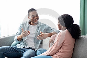 Positive black man and woman having conversation at home