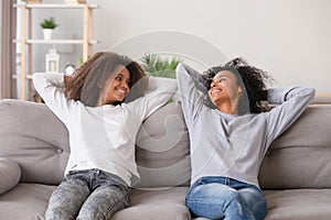 Positive black mother and daughter resting on couch at home