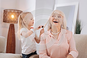 Positive blonde girl brushing her grandmothers hair
