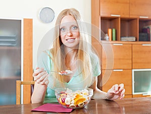 Positive blonde woman eating fruit salad