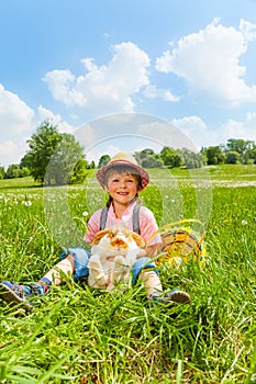 Positive boy wearing hat and hugging rabbit