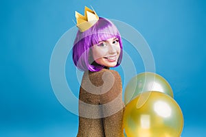 Positive brightful emotions of joyful young woman with cut purple hair celebrating party with balloons on blue