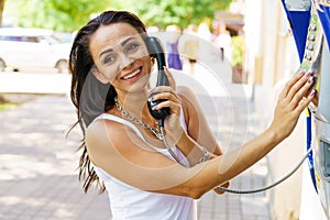 Positive brunette woman holding telephone receiver calls through stationery