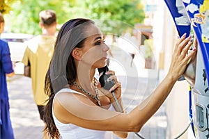 Positive brunette woman holding telephone receiver calls through stationery