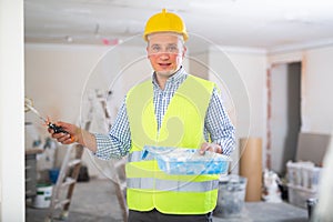 Positive builder painting wall in apartment