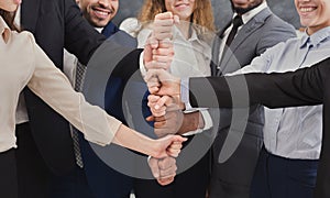 Positive business people putting fists on top of each other