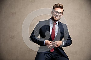 Positive businessman adjusting his jacket and laughing